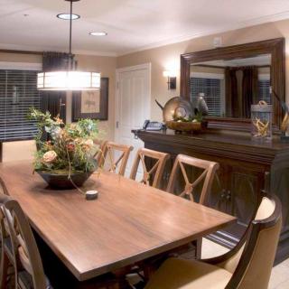 A well-decorated dining room featuring a large wooden table, elegant chairs, and stylish lighting.