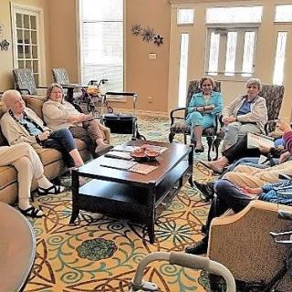 A group of seniors sitting in a living room having a discussion.