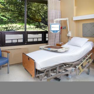 A hospital room with a bed, medical equipment, and a window with an outdoor view.