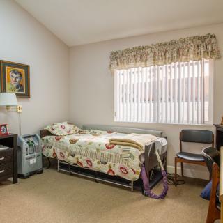 A cozy bedroom with a single bed, adorned with floral bedding and warm decor.