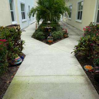 A beautifully landscaped pathway surrounded by lush greenery and decorative flower pots.