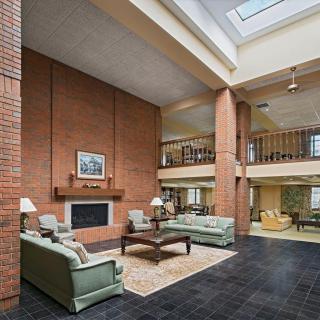 A spacious living room featuring brick walls, a fireplace, and a skylight.