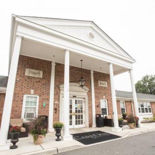 A traditional brick building entrance with white columns and a classical architectural style.