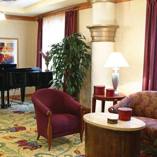 A cozy hotel lobby featuring a grand piano, comfortable seating, and elegant decor.