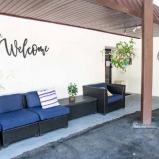 A cozy outdoor seating area with blue cushioned chairs and a 'Welcome' sign on the wall.