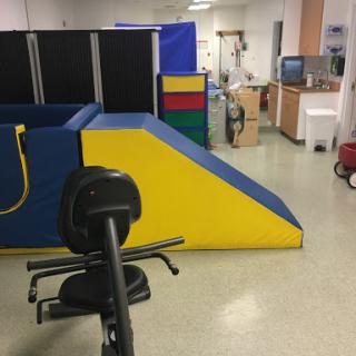 A colorful play and therapy area equipped with ramps and mats, designed for rehabilitation activities.