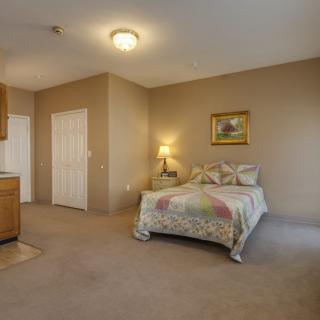 A cozy bedroom with a single bed, lamp, and a painting on the wall.