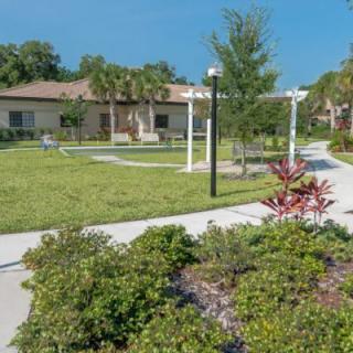 A serene garden with a winding pathway and a building in the background.