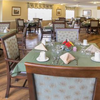 A neatly arranged dining room with tables set for a meal, featuring floral centerpieces and elegant decor.