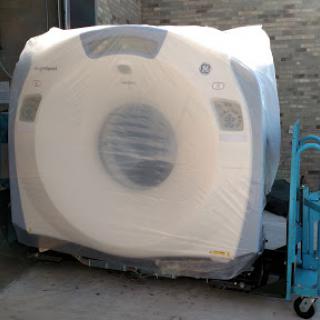 A CT scanner wrapped in protective plastic, ready for transport.