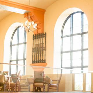 Bright and airy restaurant interior with large arched windows and elegant furniture.