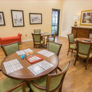 A cozy room with tables and chairs set up for games, featuring a wooden floor and decorative artwork on the walls.
