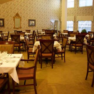 A spacious and elegantly arranged dining area, featuring neatly set tables and comfortable chairs.