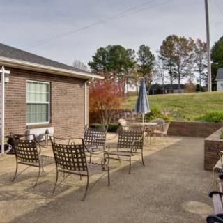 A cozy outdoor patio with metal chairs and a garden umbrella beside a brick house.