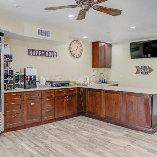 A modern kitchen with wooden cabinets, a ceiling fan, and various appliances.