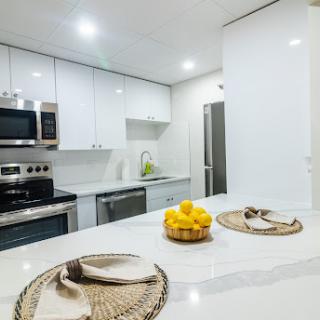 A modern, sleek kitchen featuring white cabinets and a stylish countertop, adorned with a bowl of fresh lemons.