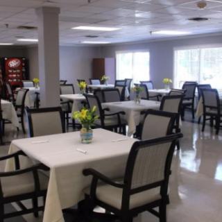 A spacious dining room with neatly arranged tables and chairs, featuring floral centerpieces.
