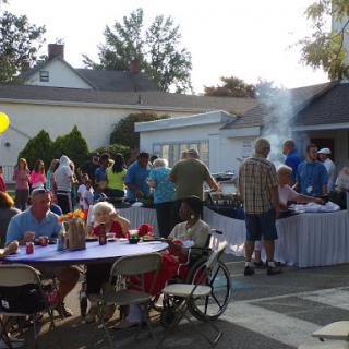 A lively community barbecue gathering with friends and family enjoying food and each other's company.