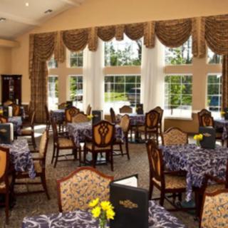 An elegant dining room with beautifully arranged tables and chairs, featuring large windows and decorative curtains.