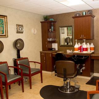 An interior view of a hair salon with chairs, a mirror, and hair styling equipment.