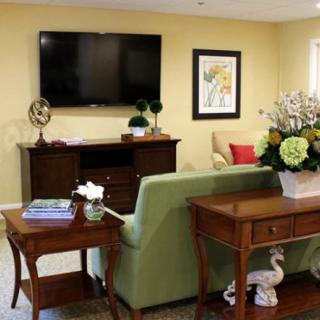 A well-decorated living room with a sofa, tables, and a television mounted on the wall.