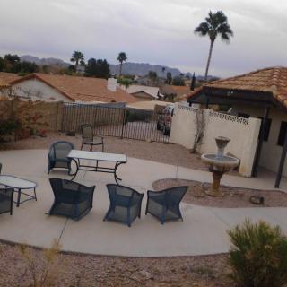 An outdoor patio with seating area in a desert setting, featuring palm trees and an overcast sky.