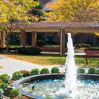 A serene garden with a flowing fountain surrounded by autumn foliage.
