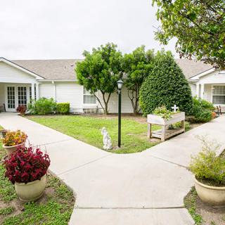 A charming white house with a well-maintained garden and pathways.