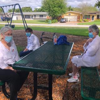 Seniors enjoying a sunny day in the park while practicing social distancing.
