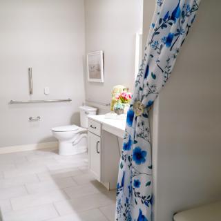 A modern bathroom with a floral shower curtain and clean white decor.