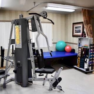 A well-equipped gym area featuring a multi-station weight machine, exercise balls, and additional training equipment.