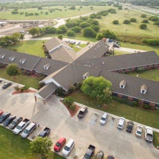 Aerial view of a building with a surrounding parking lot in a rural landscape.