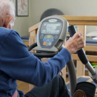 An elderly person using fitness equipment indoors to stay healthy.