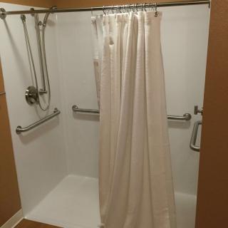 An accessible shower with grab bars and a handheld showerhead.