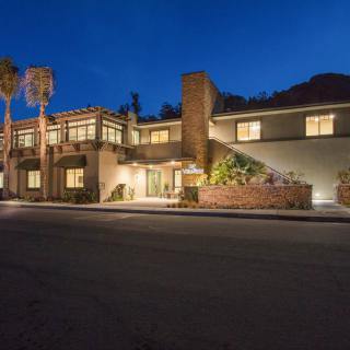 A modern house illuminated at night with palm trees in the foreground.