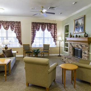 A cozy living room featuring a fireplace, comfortable seating, and large windows with elegant curtains.