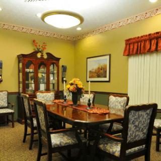 A warmly lit dining room with a wooden table, chairs, and a china cabinet.