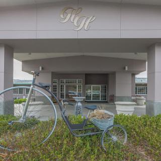 A charming entrance featuring a decorative bicycle and wheelbarrow amidst lush greenery.