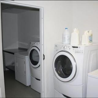 A laundry room with a washing machine and dryer, along with detergent bottles on top.