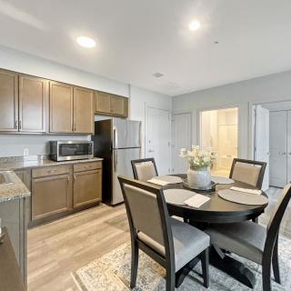 A modern kitchen and dining area featuring a round table set for four, with wooden cabinets and stainless steel appliances.