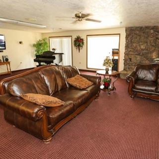 A cozy living room featuring a leather sofa, carpet flooring, and a stone fireplace.
