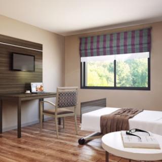 A modern hotel room featuring minimalist design with a workspace and large windows.