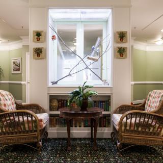 A cozy seating area with wicker chairs and decorative swords hanging above a window.