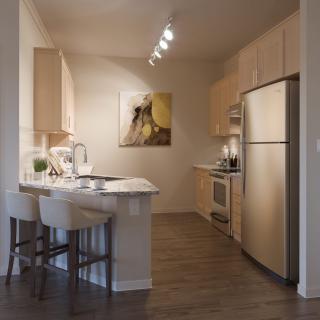 A modern kitchen with stainless steel appliances and a breakfast bar.
