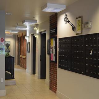 A hallway with multiple mailboxes attached to a brick wall and overhead lighting.