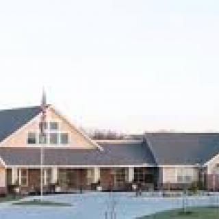 A residential-style building with a peaked roof and wide driveway.