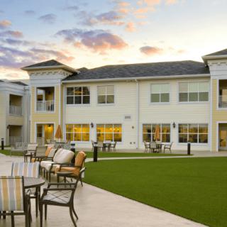 A modern residential building with outdoor seating and a well-maintained lawn at sunset.