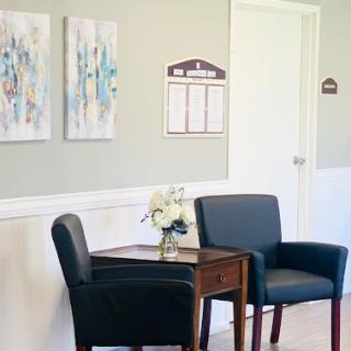 A cozy waiting room featuring modern artwork and comfortable seating.