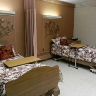 A hospital room with two beds, each equipped with bedside tables and separated by a curtain.