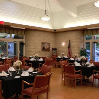 A beautifully arranged dining area featuring tables set with black tablecloths and floral centerpieces, creating an elegant atmosphere.